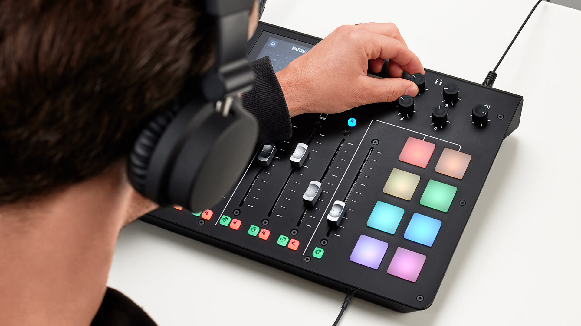 Person with headphones adjusting volume knob on RØDECaster Pro