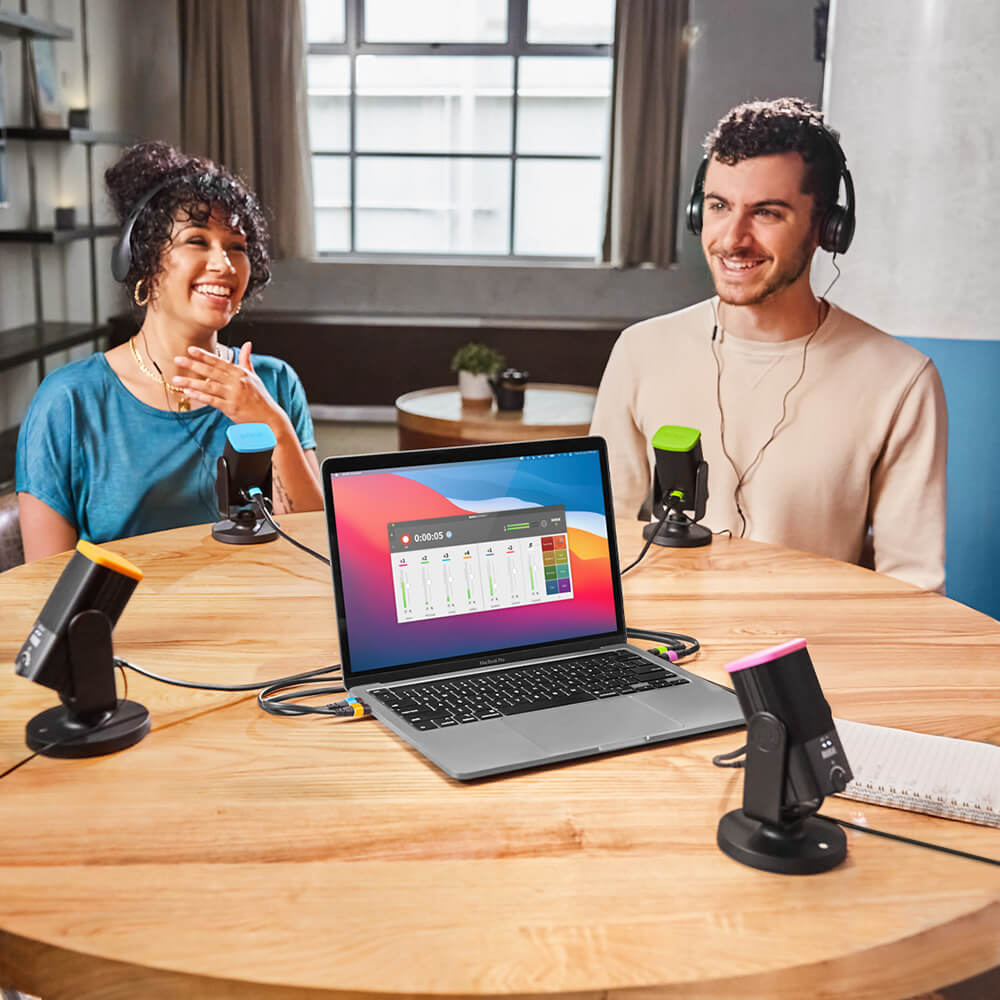 Two people podcasting with NT-USB Minis connected to MacBook showing RØDE Connect