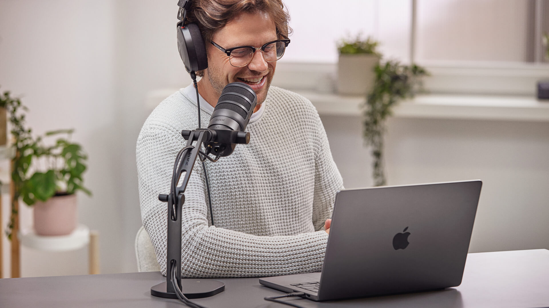 Man wearing NTH-100 using MacBook connected to PodMic USB on DS2